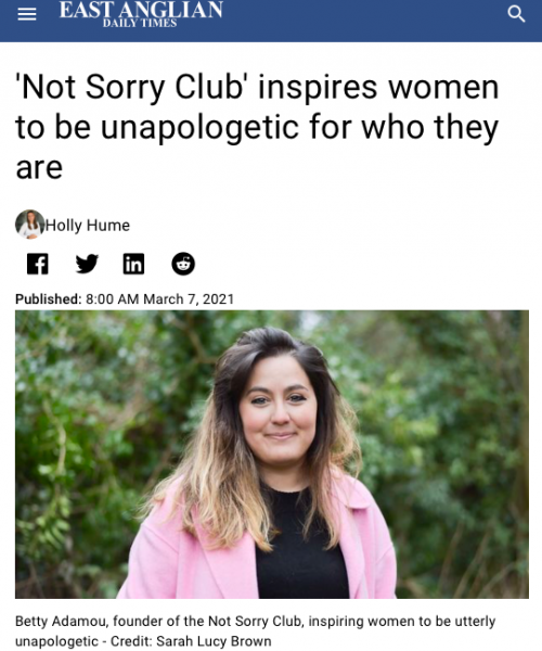 Betty Adamou, the Not Sorry Club founder, is photographed against a leafy background, wearing a black top and pink coat, looking directly at the camera