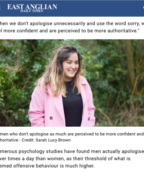 Betty Adamou, the Not Sorry Club founder, is photographed against a leafy background, wearing a black top and pink coat